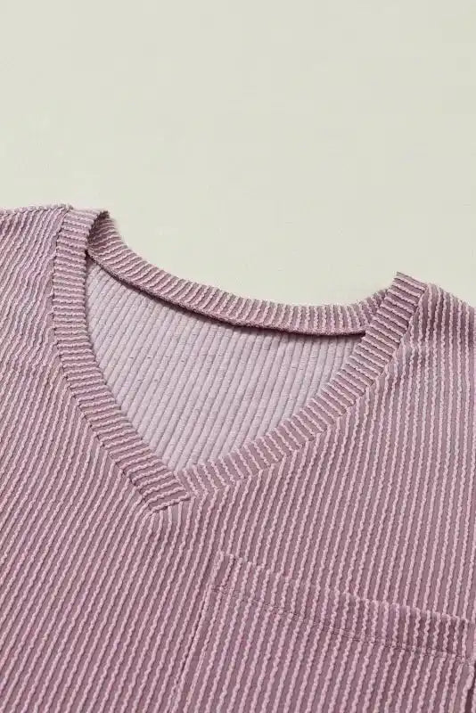 Close-up of V-neckline on mauve pink corded T-shirt, showcasing ribbed texture and soft fabric for a comfortable, relaxed fit.