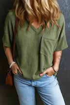 Women's corded V-neck loose T-shirt in olive green with chest pocket, styled casually with light blue jeans for a relaxed daily look.