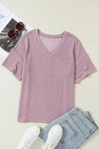 Flat lay of mauve pink corded V-neck T-shirt with chest pocket, paired with jeans and sneakers, ideal for casual women’s fashion.