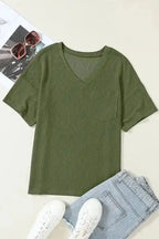 Flat lay of olive green corded V-neck loose T-shirt with chest pocket, paired with denim and sneakers for a casual outfit idea.
