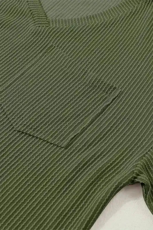 Detailed view of chest pocket on olive green corded V-neck T-shirt, emphasizing ribbed texture and casual design for women’s fashion.