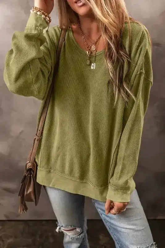 Casual winter outfit featuring Women's Jungle Green Textured Sweatshirt with ribbed texture and slouchy fit, styled with distressed jeans.