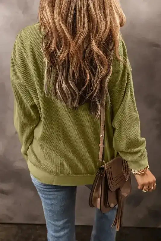 Back view of Women's Jungle Green Textured Sweatshirt showing relaxed fit and ribbed fabric, paired with a brown crossbody bag.