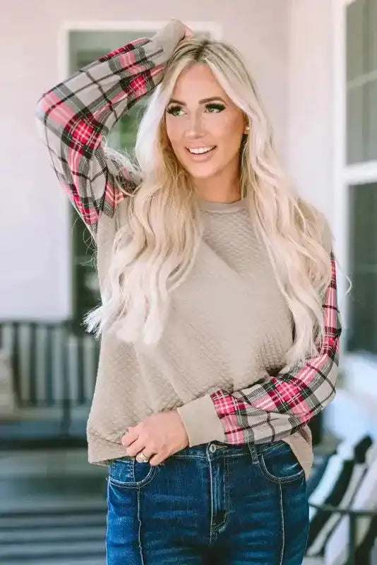 Front view of quilted hooded dress with red plaid sleeves, styled casually with jeans for a cozy and fashionable look.