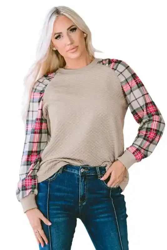 Model wearing quilted hooded dress with plaid sleeves, styled with jeans for a relaxed and fashionable look.