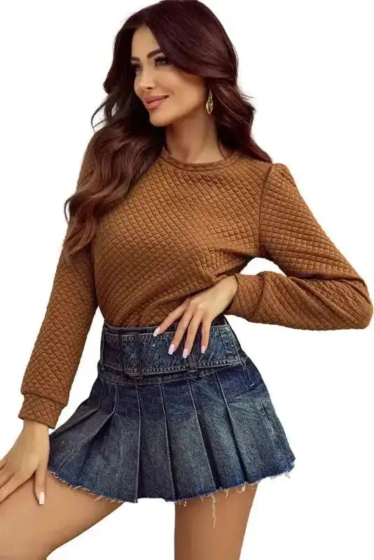 Model posing in camel quilted hooded dress and denim mini skirt, showcasing a trendy and cozy outfit for everyday wear.