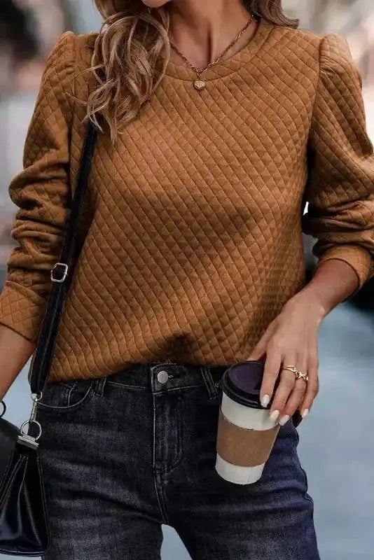 Brown quilted top with puff sleeves, styled with dark jeans and accessories, showcasing a chic and cozy fall outfit.
