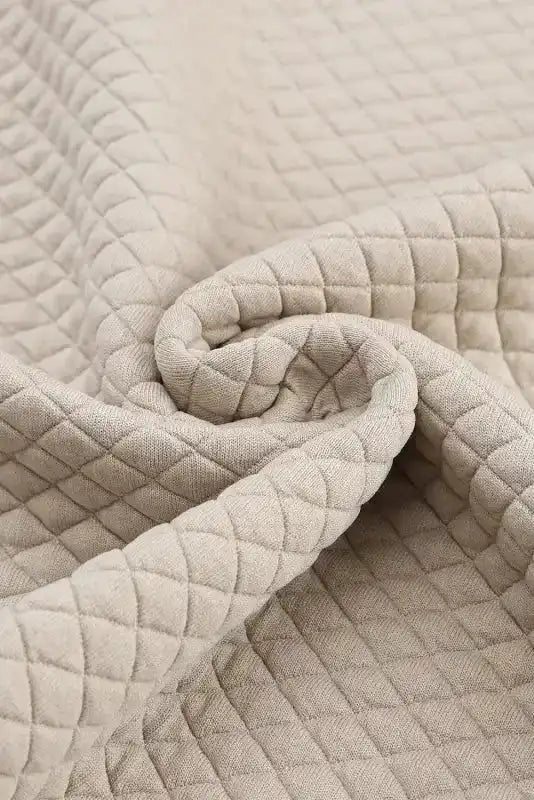 Fabric close-up of quilted hooded dress, emphasizing the soft, textured diamond pattern for warmth and comfort.