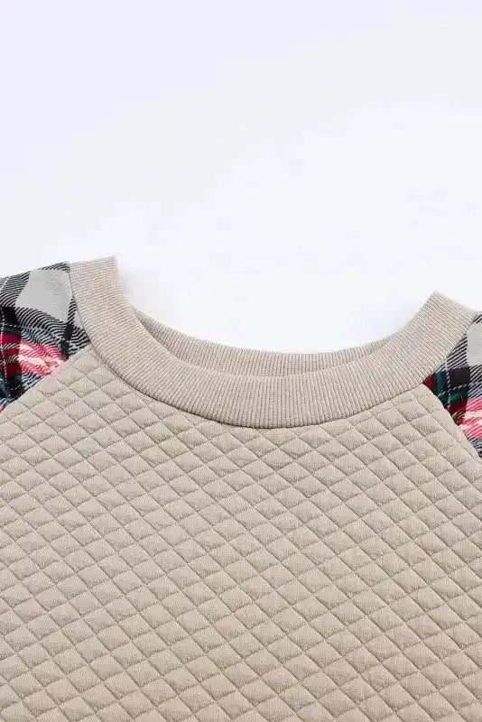 Close-up of neckline on quilted hooded dress with plaid sleeves, featuring ribbed collar and diamond quilt pattern.