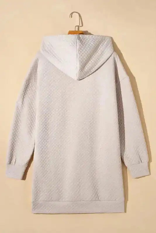 Back of Quilted Hooded Dress - Kangaroo Pocket on hanger, featuring quilted fabric and relaxed fit.