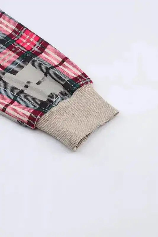 Detail of cuff on plaid sleeve of quilted hooded dress, showing ribbed trim and vibrant red plaid pattern.