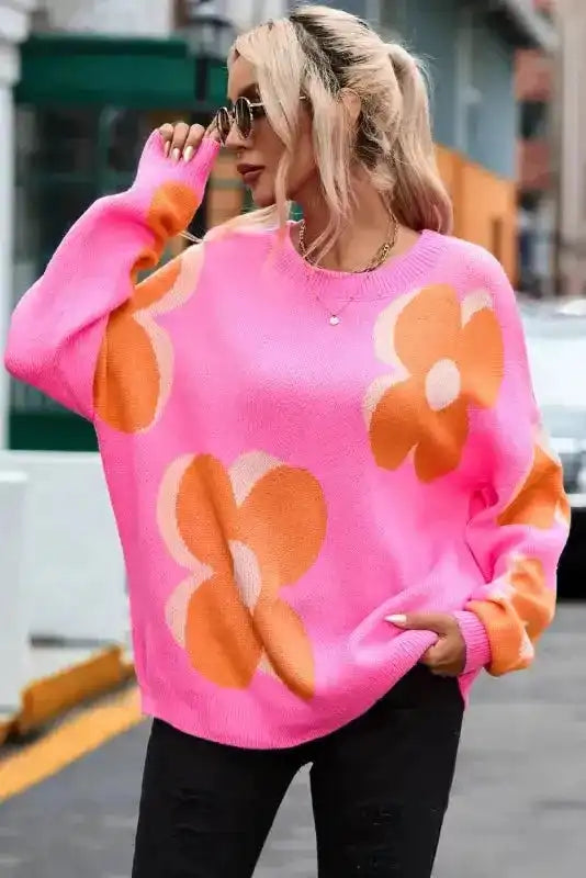 Bright pink floral drop shoulder sweater with orange flowers, styled oversized for bold streetwear fashion.