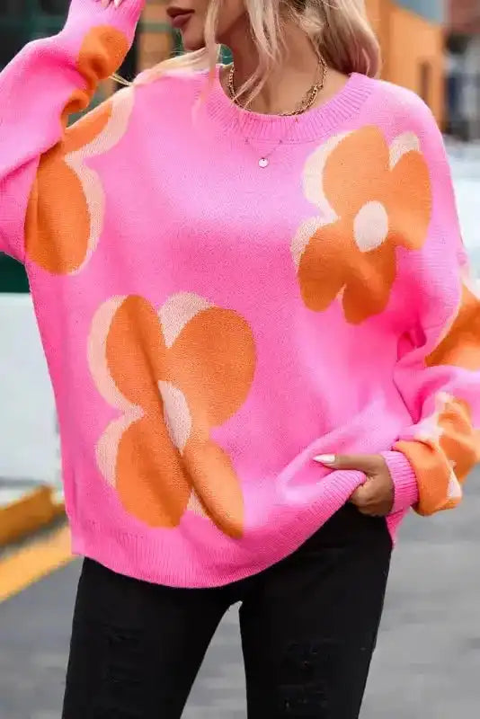 Close-up of Khaki Floral Drop Shoulder Sweater highlighting oversized orange floral patterns on vibrant pink knit fabric for fall fashion.