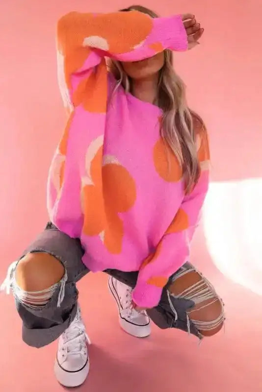 Model crouching in Khaki Floral Drop Shoulder Sweater with bold floral design, styled with ripped jeans for a trendy, laid-back vibe.