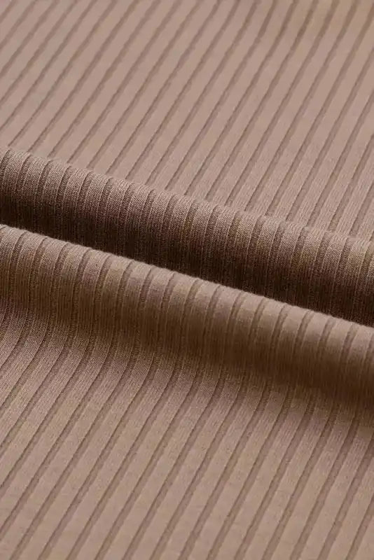Macro view of ribbed fabric on khaki V-neck knit top, emphasizing texture and material quality.
