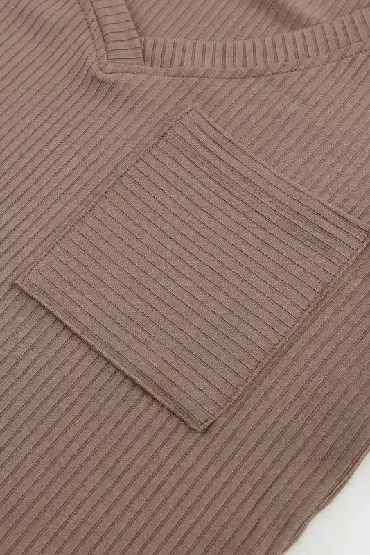 Close-up of chest pocket on khaki V-neck knit top, showcasing ribbed texture and neat stitching.