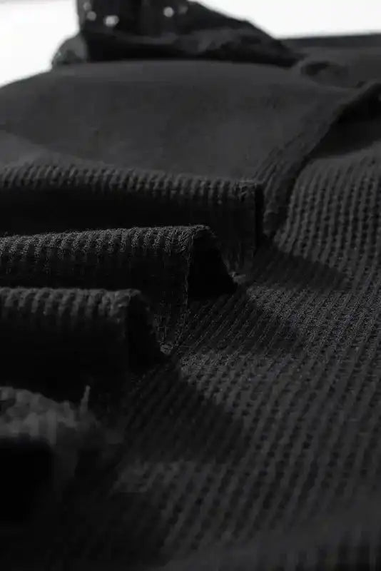 Folded view of Black Lace Sleeve Textured Top showing soft, textured knit and lace shoulder detail.