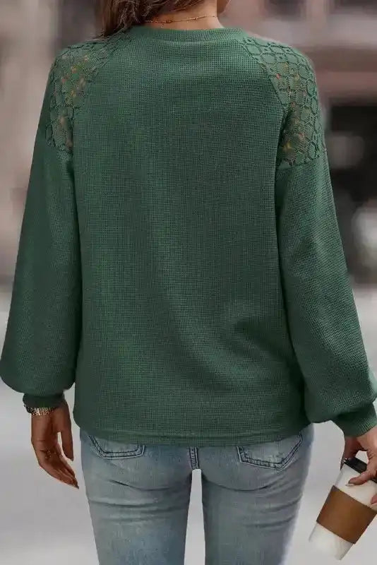 Back view of Lace Sleeve Textured Top in green, showing lace shoulder detail and relaxed fit, paired with light-wash jeans. Elegant fall fashion top.