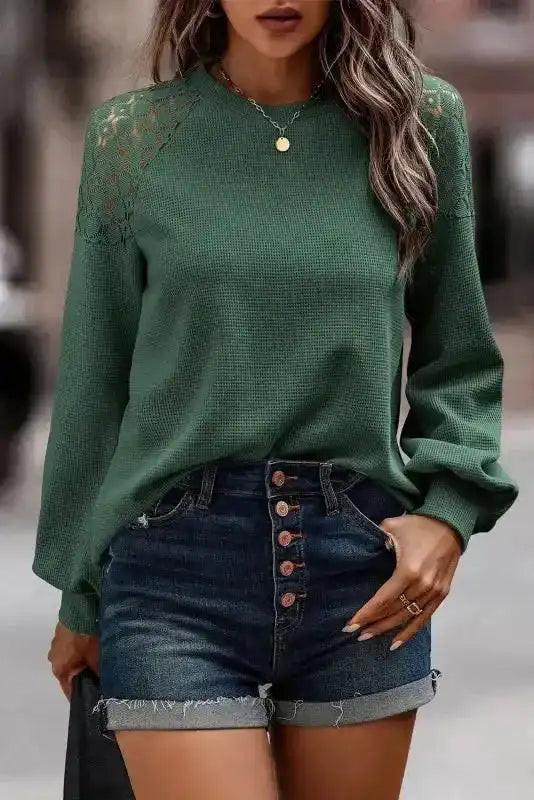 Lace Sleeve Textured Top in forest green with long sleeves and crochet lace shoulders, styled with high-waisted denim shorts. FashionFitz women tops.