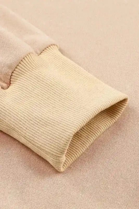 Detailed view of ribbed cuff on beige bishop sleeve sweatshirt, showcasing fine knit texture and cozy winter-ready material.