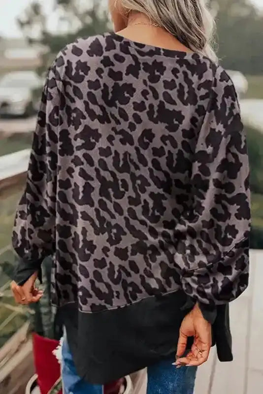 Back view of Leopard Patchwork Bishop Sleeve Sweatshirt showcasing full leopard print design on sleeves and upper back with solid black hem.