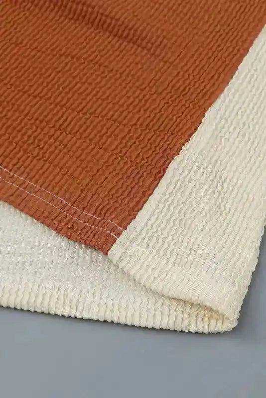 Hem detail of rust and beige ribbed knit fabric on long sleeve tops leopard patchwork color block ribbed long with visible stitching.