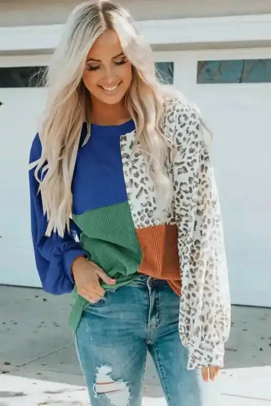 Smiling model in blue, green, rust, and leopard print long sleeve tops leopard patchwork color block ribbed long with ripped jeans.