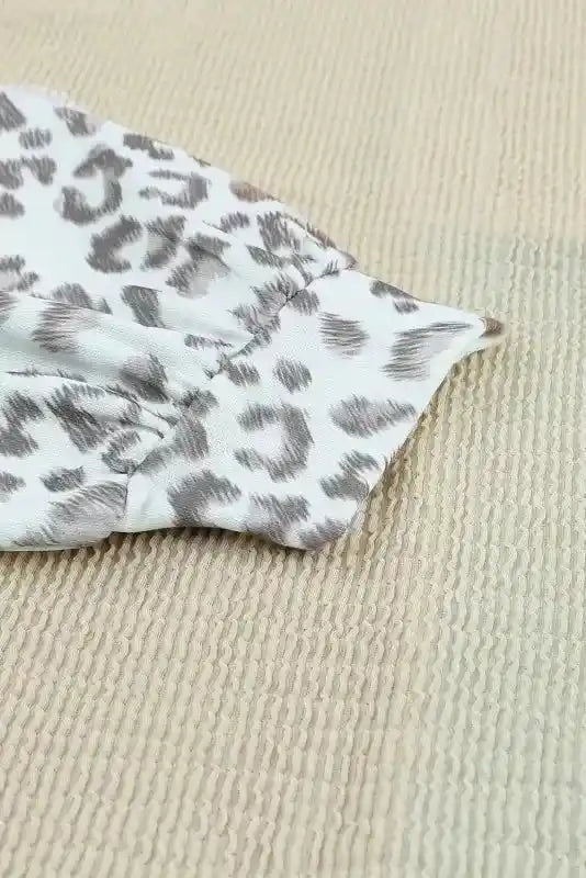 Detailed view of leopard print sleeve cuff on long sleeve tops leopard patchwork color block ribbed long with ribbed beige fabric.