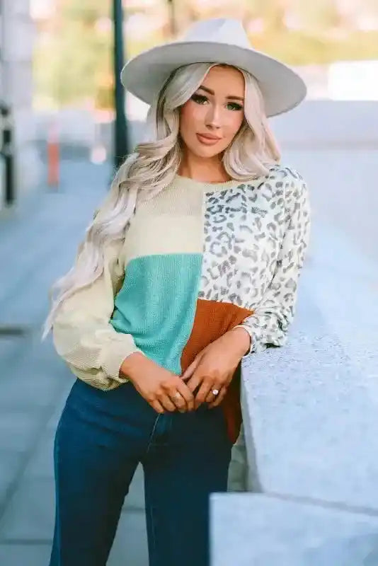 Stylish leopard patchwork ribbed long sleeve top with color block design, paired with jeans and a white hat for fall.