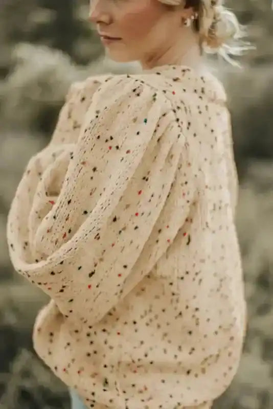 Side view of beige colorful cable knit sweater with balloon sleeves and dotted pattern. A stylish winter top for casual wear.