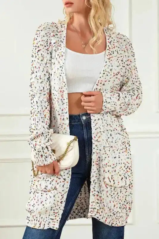 Model wearing colorful cable knit sweater cardigan with multicolor dots, styled with jeans and a white crop top for daily winter wear.