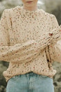 Colorful cable knit sweater in beige with multicolor dots, styled with puff sleeves for cozy winter wear. Ideal for layering with denim.