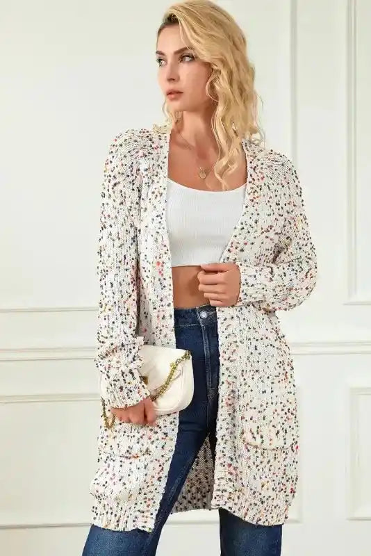 Colorful cable knit sweater cardigan styled with a white crop top and jeans, showcasing cozy winter fashion with multicolor details.