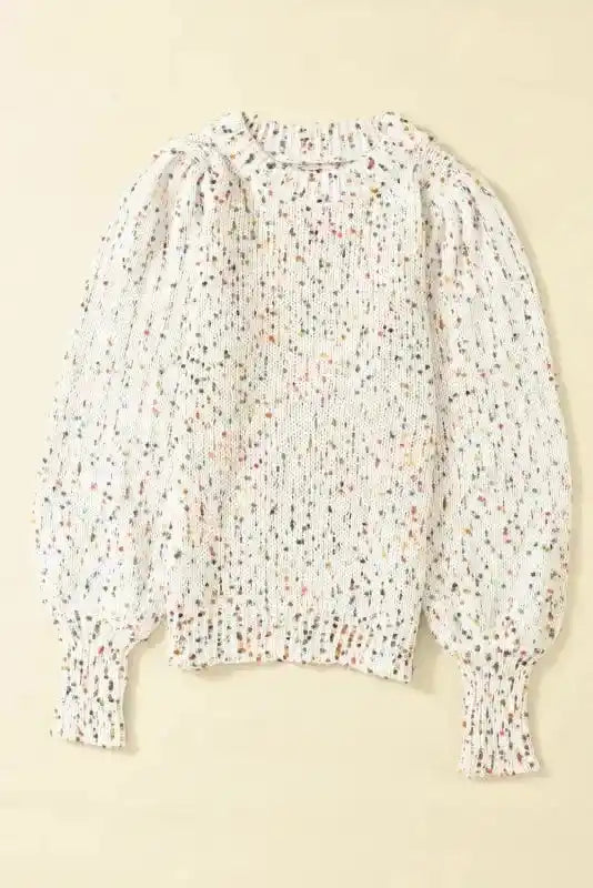 Flat lay of white colorful cable knit sweater with multicolor dots and ribbed neckline. A cozy and stylish winter top for layering.