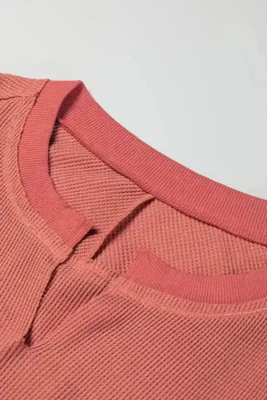 Detail of the slit neckline on dusty rose Women's Exposed Seam Waffle Knit Tunic Top, showing ribbed waffle knit texture.