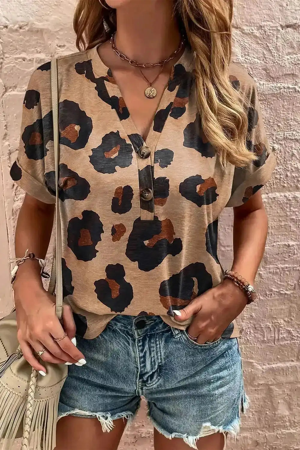 Light French Beige Leopard Blouse with V-neck and short sleeves, styled with denim shorts for a casual summer look. Features bold leopard print and button front.
