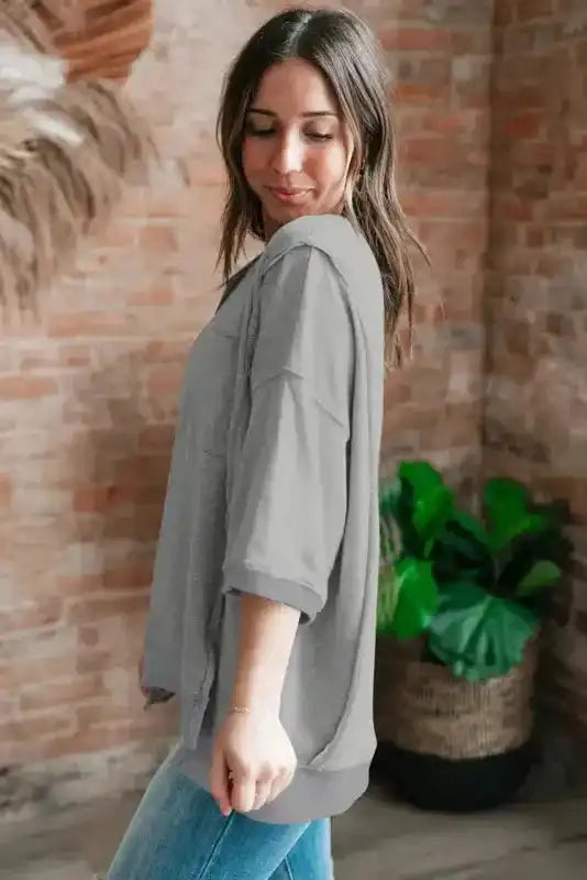 Grey baggy t-shirt with side slits and exposed seam detail shown from side angle