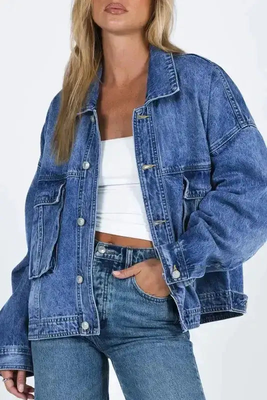 Women's loose denim jacket in blue with drop shoulders and chest pockets, styled casually with jeans for everyday wear.