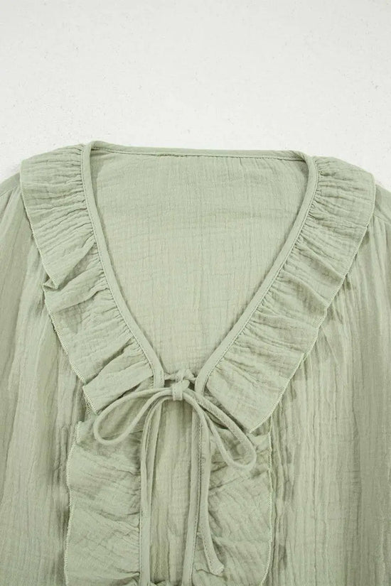 Close-up of Meadow Cotton Blouse neckline showing ruffle trim and tie detail, crafted from soft, breathable cotton fabric in solid green.