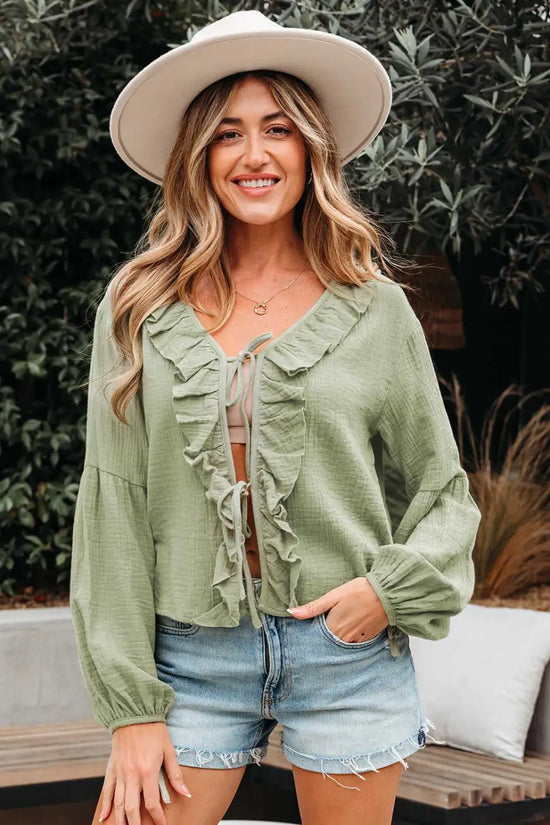 Front view of Meadow Cotton Blouse in soft green with ruffle details and tie closure, styled for a chic and breezy everyday outfit.