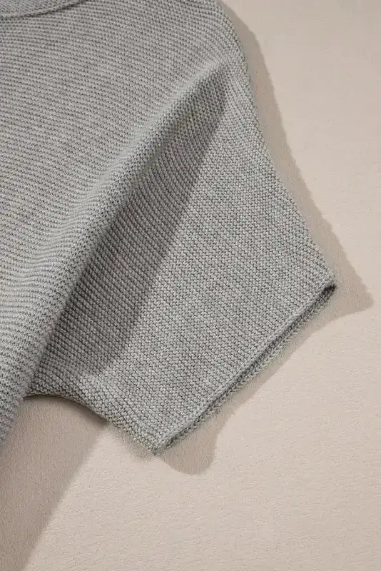Close-up of short bat sleeve on grey knit sweater highlighting fine texture and soft fabric. Great for daily casual outfits.