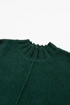Close-up of ribbed mock neckline on dark green batwing knit sweater, showcasing fine knit texture and detail.