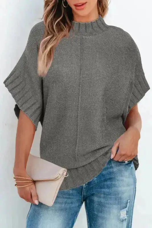Gray short sleeve mock neck sweater paired with distressed jeans and a beige clutch for a casual chic look.