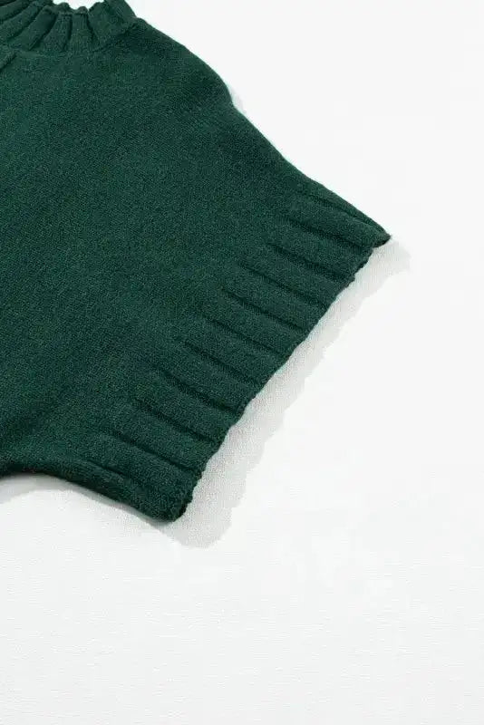 Detailed view of ribbed short sleeve on dark green batwing knit sweater, highlighting quality craftsmanship.