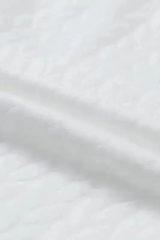 Detailed fabric view of white cable knit sweatshirt, highlighting the soft and textured knit pattern.