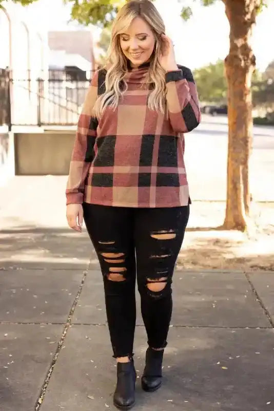 Model wearing plus size mineral red plaid top with asymmetric neck, paired with ripped black jeans for a casual street style look.