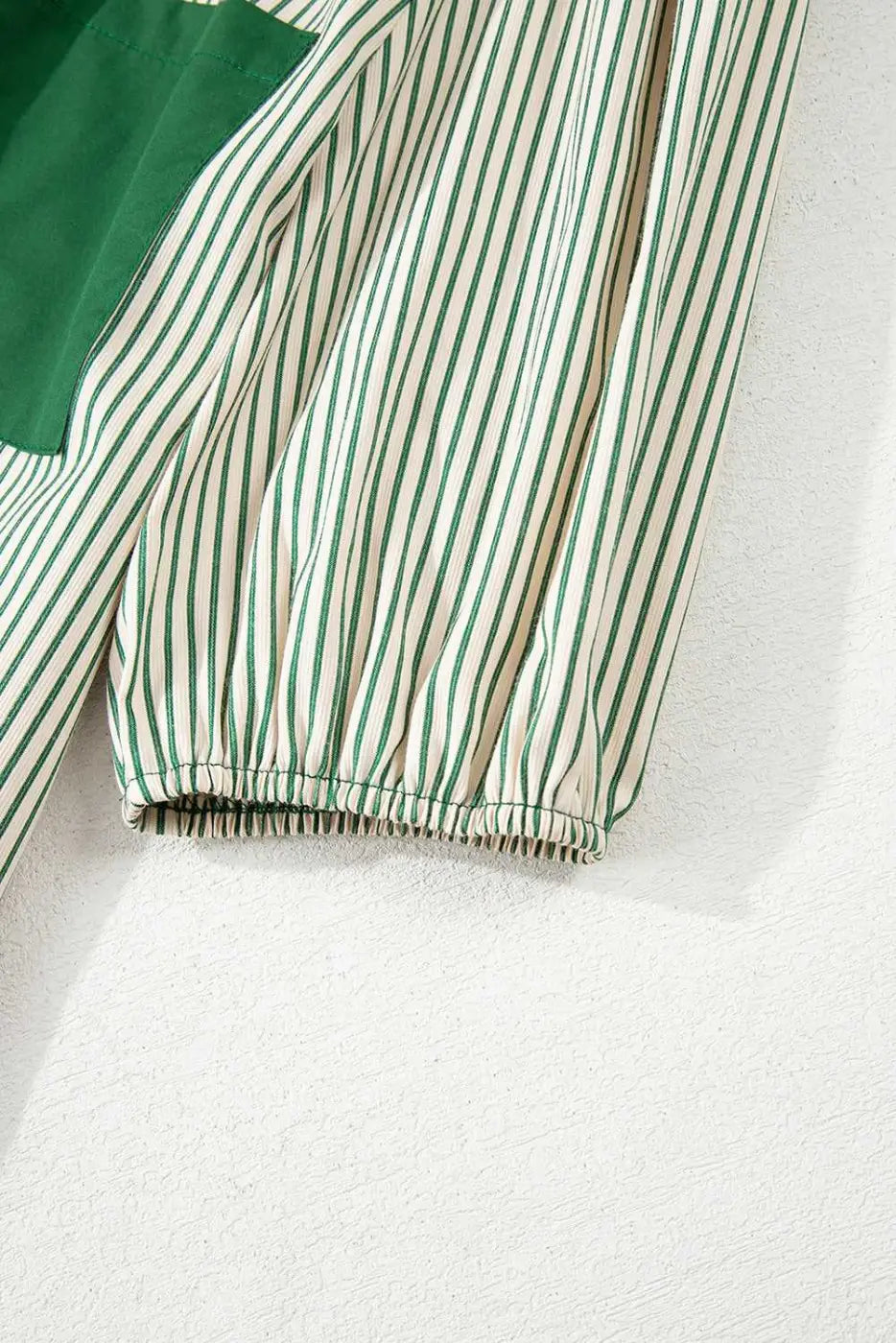 Close-up of puff sleeve on green striped mini dress, showing elastic cuff and lightweight fabric ideal for warm-weather wear.