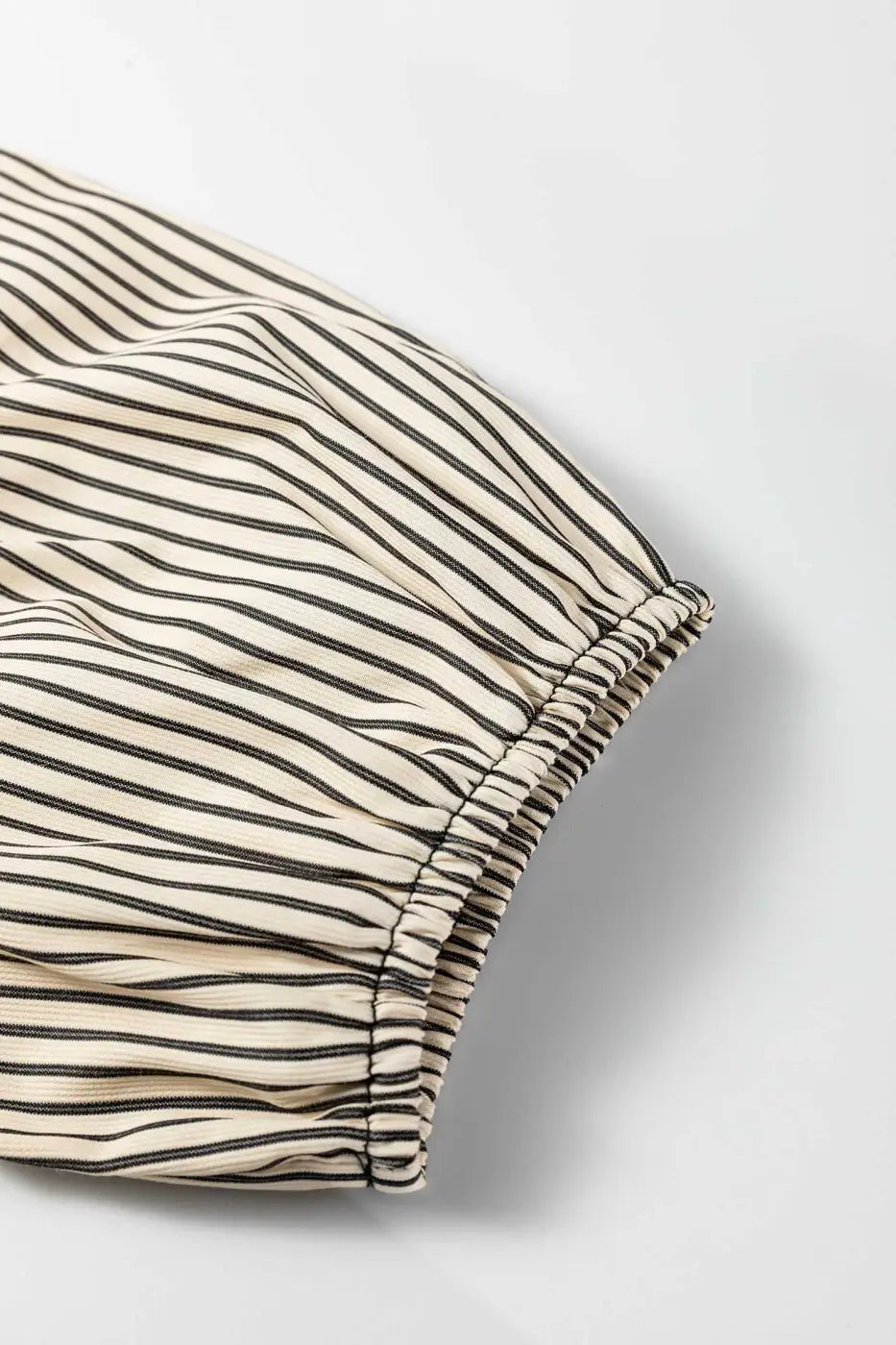 Detail of puff sleeve on Monochrome Striped Puff Sleeve Mini Dress with elastic hem and lightweight striped fabric for summer wear.