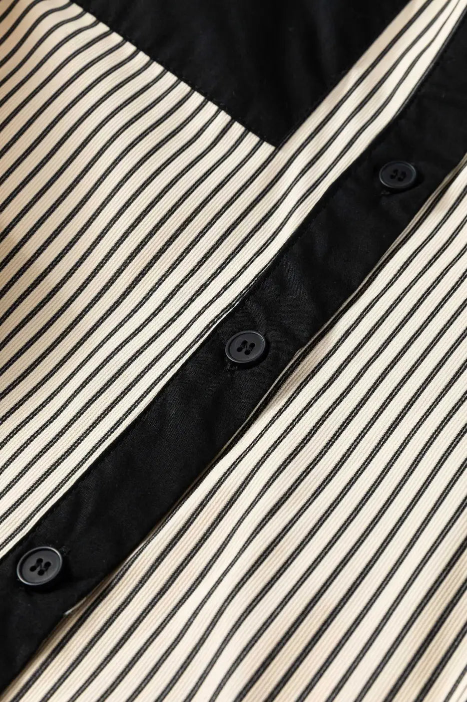 Front button placket of Monochrome Striped Puff Sleeve Mini Dress featuring black buttons and vertical stripes for a modern casual look.