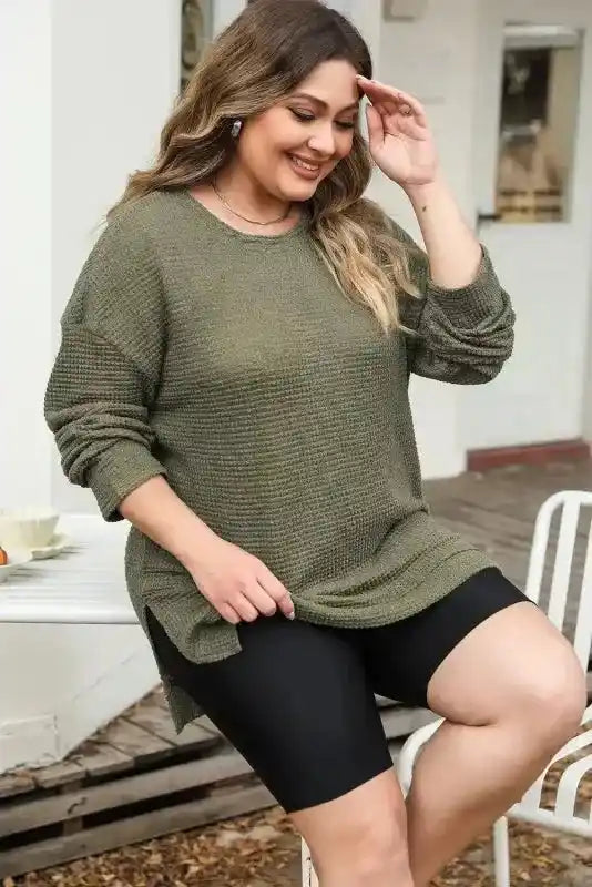 Seated model in Plus Size Moss Green Knit Top, showing off its soft waffle knit texture and relaxed long sleeve design.